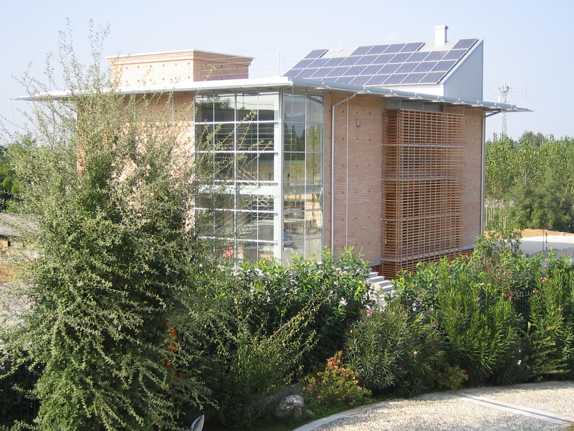 La sede di Bosio Costruzioni tra il verde, con le vetrate d’angolo e i frangisole in legno
